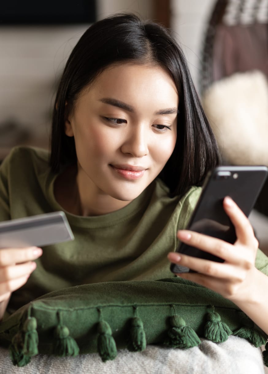 Woman holding credit card and shopping on phone