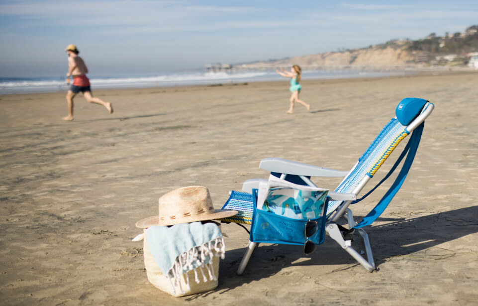 Family running on beach with chair in the foreground